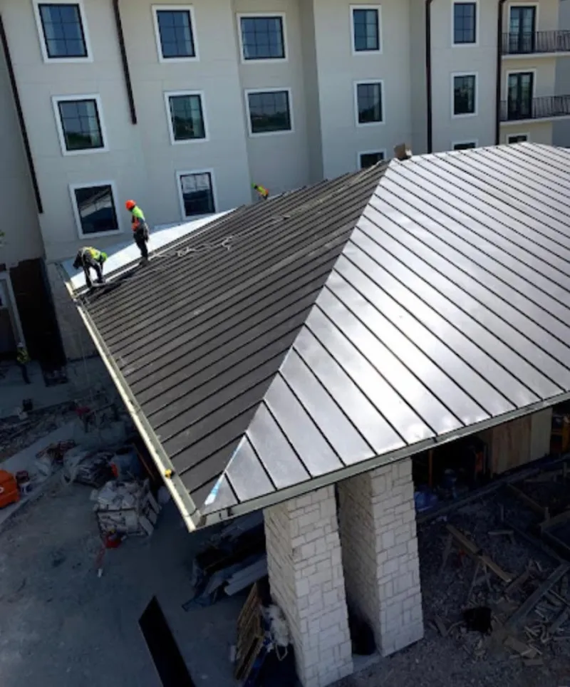 Crew installing standing seam metal roof panels on a commercial project in Billerica